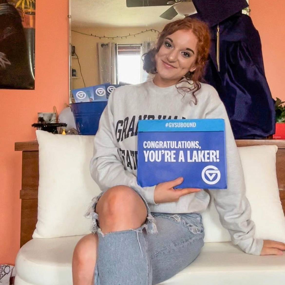 student with GVSU sweatshirt holding acceptance envelope